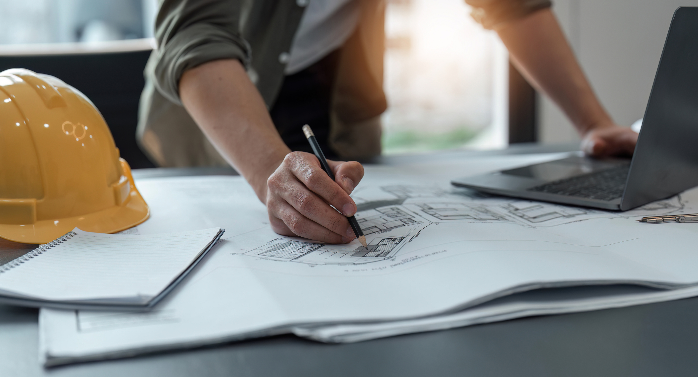 Engineer inspecting architectural plan, sketching a construction project